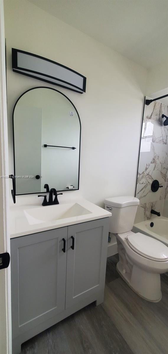 full bathroom with tiled shower / bath combo, vanity, toilet, and hardwood / wood-style flooring