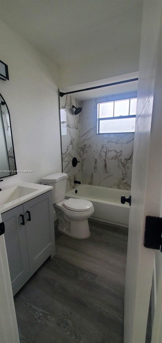 full bathroom with tiled shower / bath, toilet, wood-type flooring, and vanity