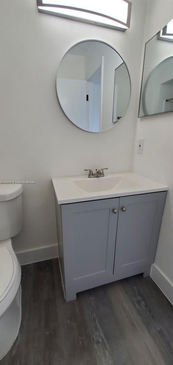 bathroom featuring wood-type flooring, toilet, and vanity