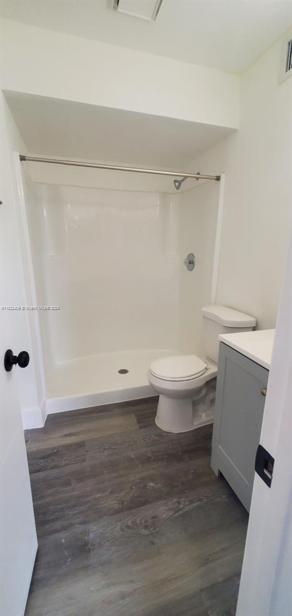 bathroom featuring vanity, toilet, wood-type flooring, and walk in shower