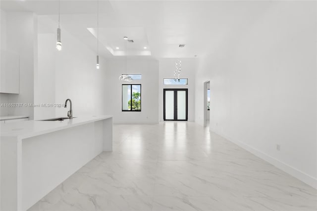 kitchen with white cabinets, hanging light fixtures, a raised ceiling, and sink