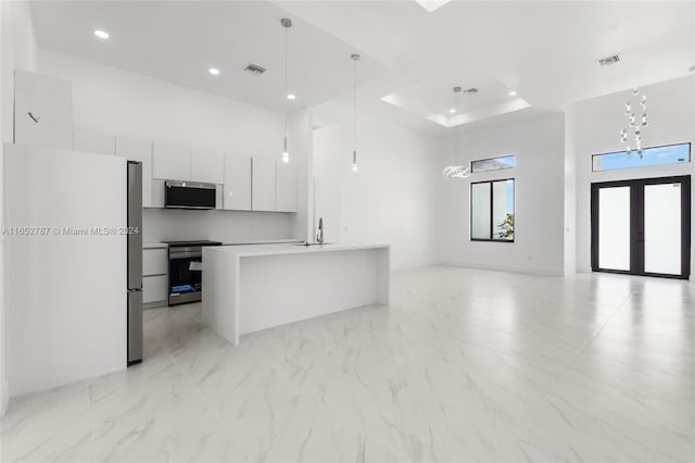 kitchen with a kitchen island with sink, pendant lighting, a chandelier, appliances with stainless steel finishes, and white cabinets