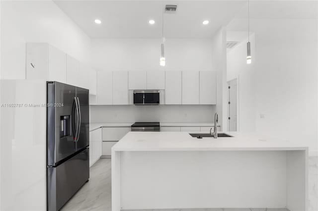 kitchen featuring decorative light fixtures, stainless steel appliances, sink, a center island with sink, and white cabinets