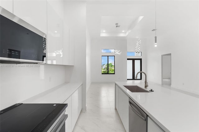 kitchen featuring pendant lighting, white cabinetry, stainless steel appliances, and sink