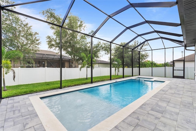 view of pool featuring glass enclosure, a lawn, and a patio