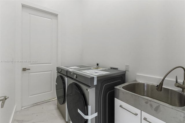 clothes washing area with cabinets, sink, and washer and clothes dryer