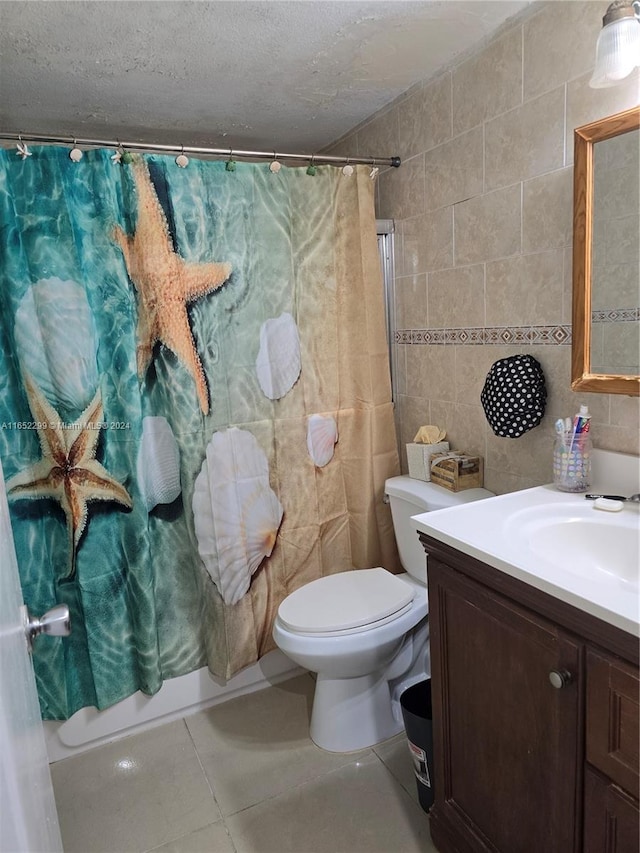 full bathroom with tile patterned floors, toilet, tile walls, shower / bath combo with shower curtain, and vanity