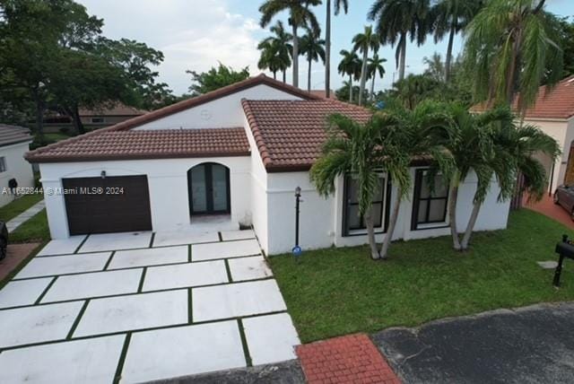 mediterranean / spanish house with a garage and a front yard