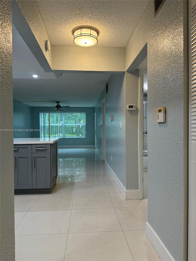 hall with a textured ceiling and light tile patterned flooring