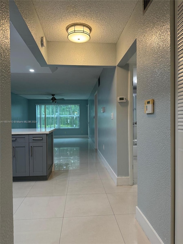 hall featuring a textured ceiling and light tile patterned floors