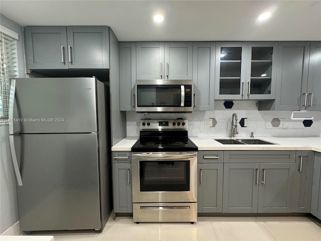 kitchen with gray cabinets, stainless steel appliances, sink, and decorative backsplash