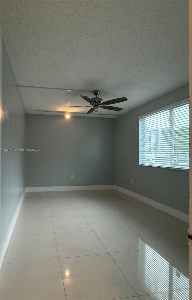 unfurnished room with ceiling fan, light tile patterned floors, and a textured ceiling