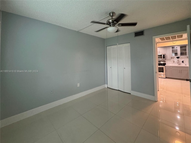 unfurnished bedroom with light tile patterned floors, sink, ceiling fan, and a closet