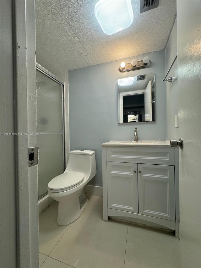 bathroom with a shower with door, vanity, toilet, and tile patterned flooring