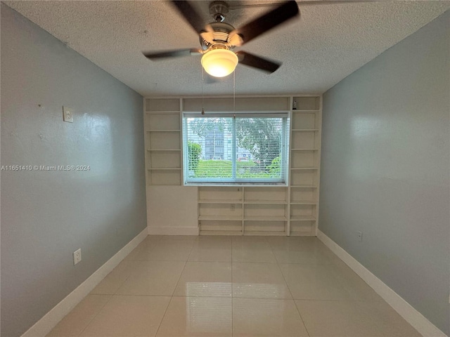 tiled empty room featuring ceiling fan and a textured ceiling