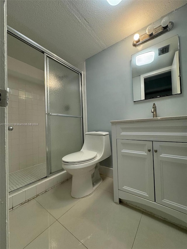 bathroom featuring vanity, toilet, tile patterned floors, and a shower with shower door