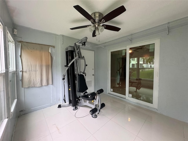 workout room featuring ceiling fan, light tile patterned flooring, and a healthy amount of sunlight