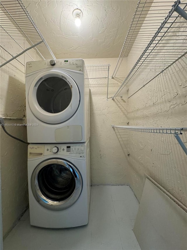 washroom with a textured ceiling and stacked washer and dryer