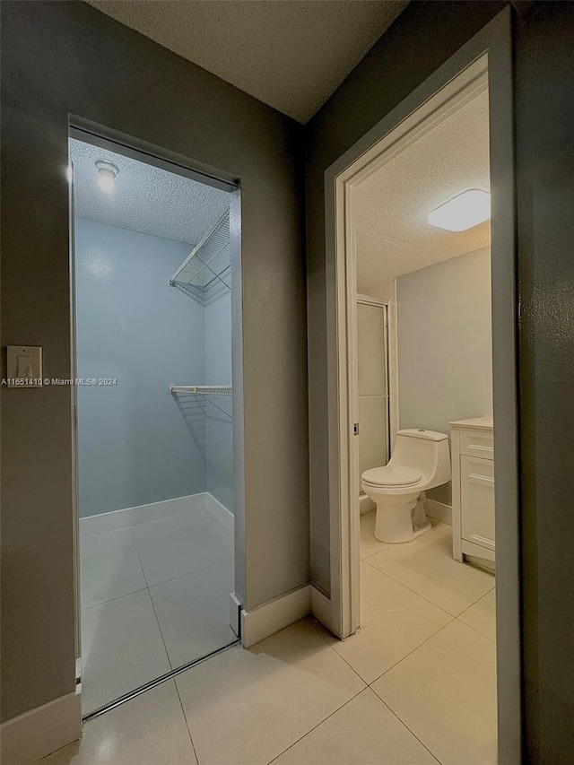 bathroom featuring tile patterned flooring, toilet, and a textured ceiling