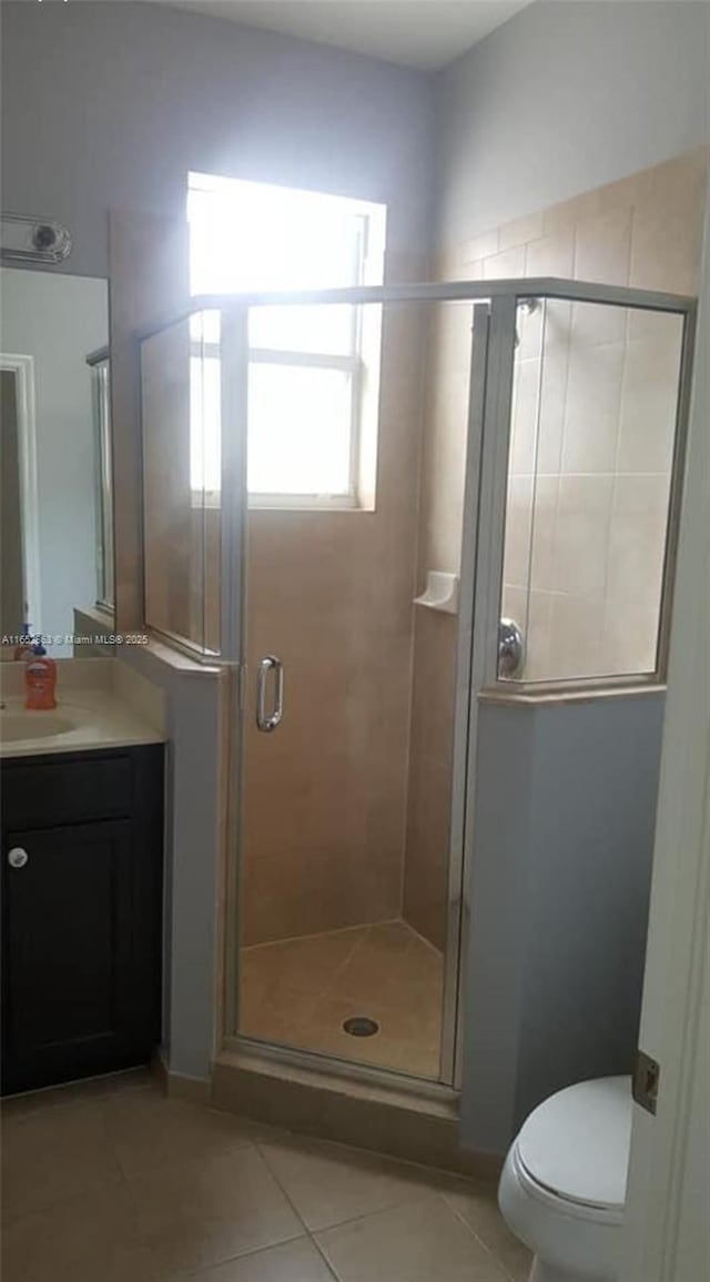 bathroom featuring a shower with door, tile patterned floors, vanity, and toilet