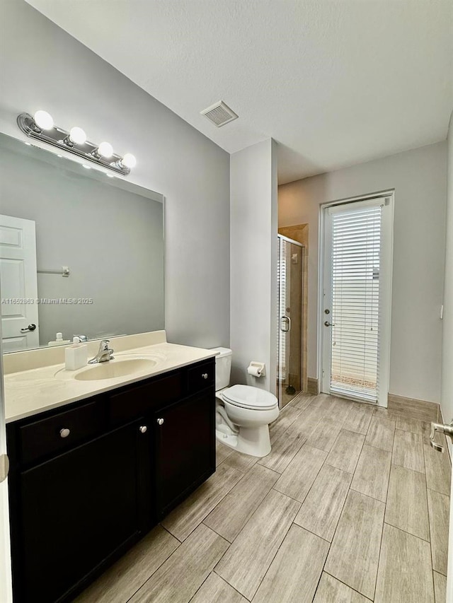 bathroom with vanity, toilet, a textured ceiling, and an enclosed shower