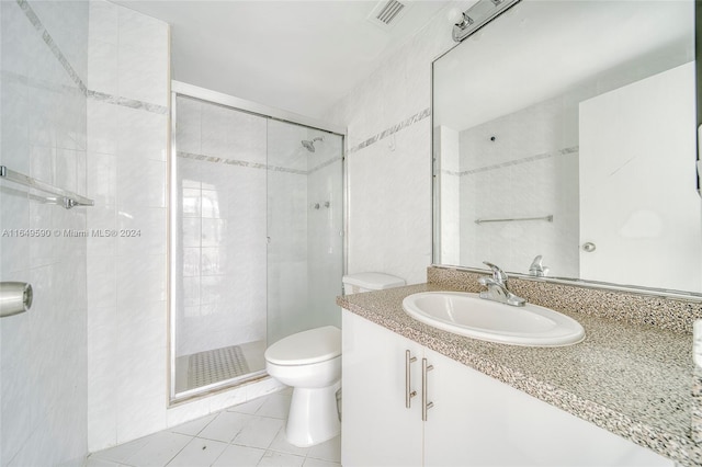 bathroom with tile walls, tile patterned flooring, walk in shower, vanity, and toilet