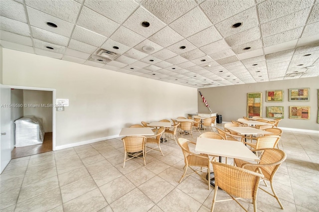 dining space with a drop ceiling and light tile patterned floors