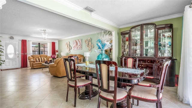 dining room featuring crown molding, light tile patterned floors, and a textured ceiling