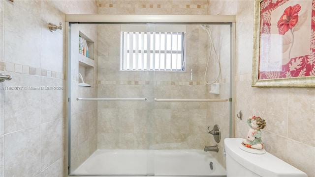 bathroom featuring toilet and bath / shower combo with glass door