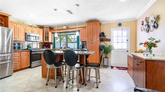 kitchen with a kitchen bar, appliances with stainless steel finishes, backsplash, a textured ceiling, and hanging light fixtures