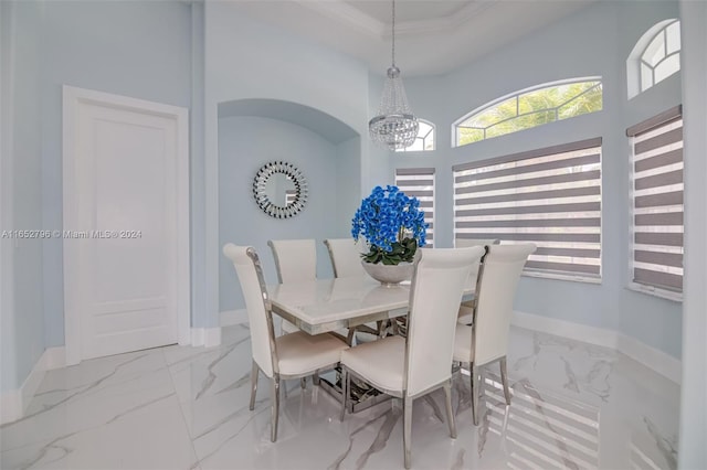 dining room featuring crown molding, a high ceiling, and a notable chandelier