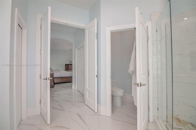 bathroom with a shower with door and toilet