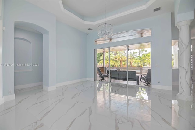 unfurnished room featuring a healthy amount of sunlight, a notable chandelier, and a tray ceiling