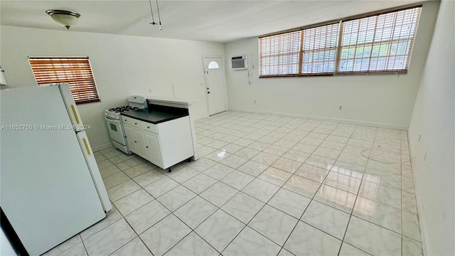 kitchen with white appliances, a wall unit AC, light tile patterned floors, and white cabinets