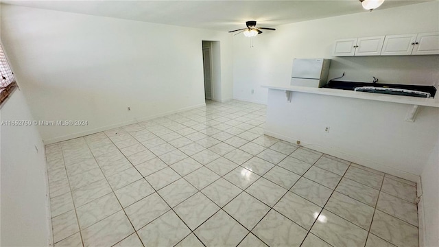 kitchen with white fridge, light tile patterned floors, a breakfast bar, white cabinetry, and ceiling fan