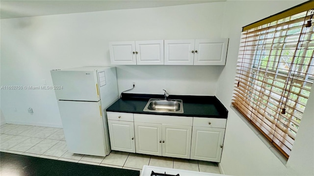 kitchen with white refrigerator, light tile patterned floors, white cabinets, and sink