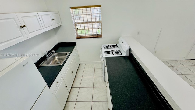 kitchen with stainless steel fridge, white cabinetry, light tile patterned floors, sink, and white gas stove