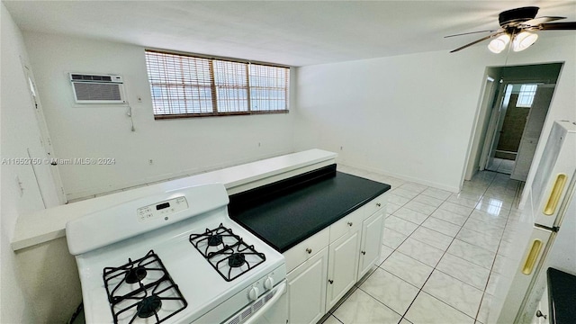 kitchen with white range with gas stovetop, a wall mounted AC, light tile patterned floors, white cabinets, and ceiling fan