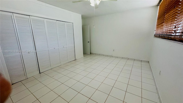 unfurnished bedroom with light tile patterned flooring, ceiling fan, and a closet