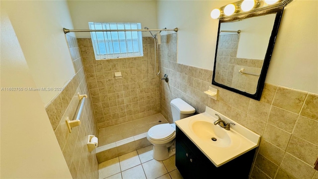 bathroom featuring toilet, tile patterned flooring, vanity, tiled shower, and tile walls