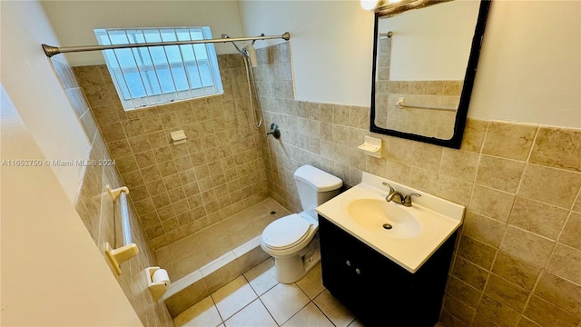 bathroom featuring vanity, toilet, tile walls, and tiled shower