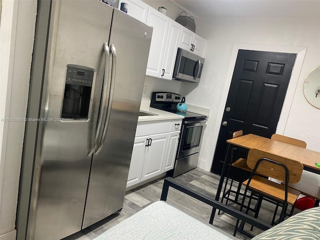 kitchen with white cabinetry, appliances with stainless steel finishes, and light hardwood / wood-style floors