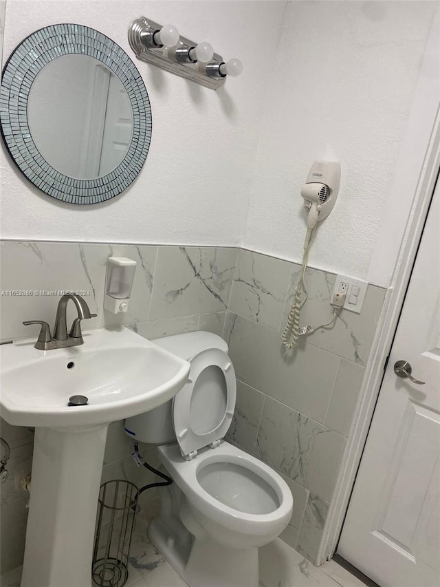 bathroom with toilet and tile walls