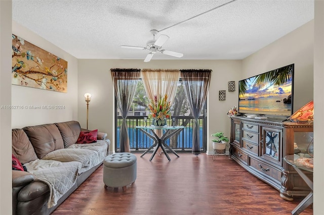 living room featuring dark wood-type flooring, a textured ceiling, and ceiling fan