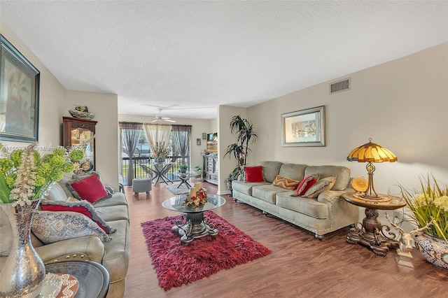 living room with a textured ceiling, dark wood-type flooring, and ceiling fan