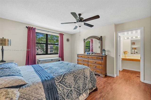 bedroom featuring a textured ceiling, hardwood / wood-style flooring, connected bathroom, and ceiling fan