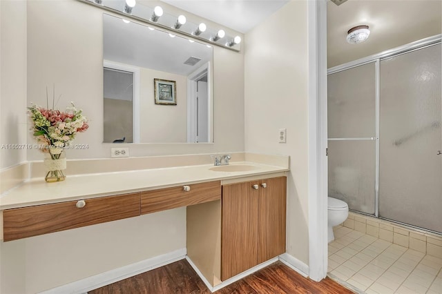 bathroom featuring vanity, toilet, hardwood / wood-style floors, and a shower with shower door