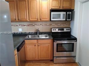 kitchen with tasteful backsplash, stainless steel appliances, sink, and light wood-type flooring