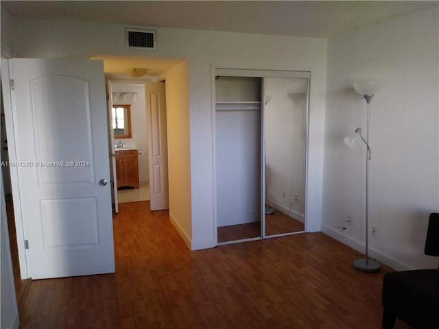 unfurnished bedroom with dark hardwood / wood-style floors and a closet