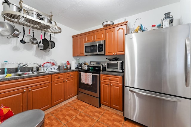 kitchen featuring a textured ceiling, sink, light tile patterned floors, and appliances with stainless steel finishes